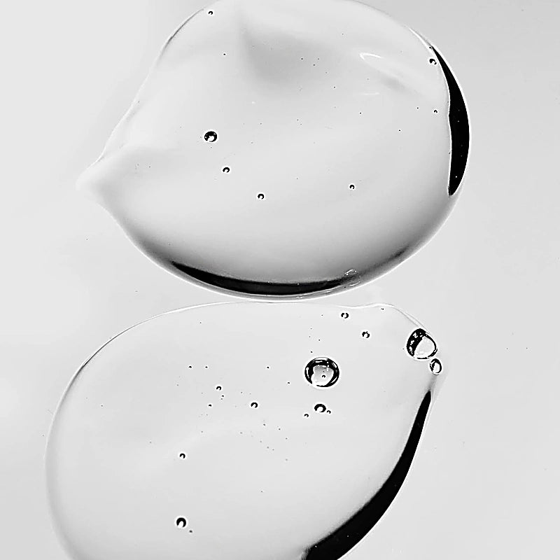 Close-up of two droplets of clear liquid on a light gray background