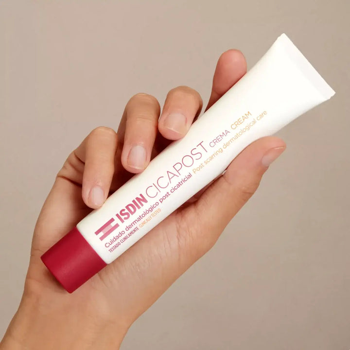 Hand holding ISDIN Cicapost Cream tube for post-scar skin care with rosehip oil and vitamin E acetate