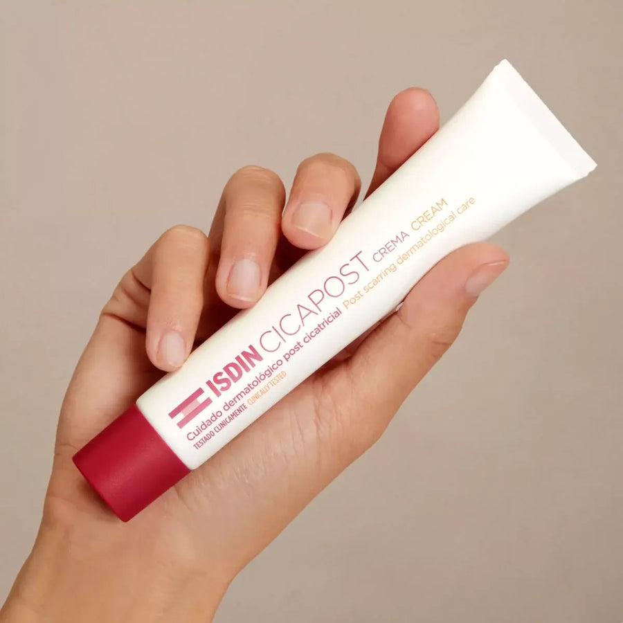 Hand holding ISDIN Cicapost Cream tube for post-scar skin care with rosehip oil and vitamin E acetate
