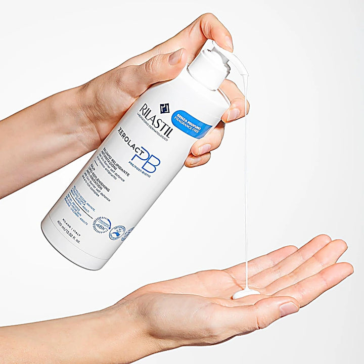 Person holding a bottle of Rilastil Zero Lacquer PB cream and applying it to their palm.