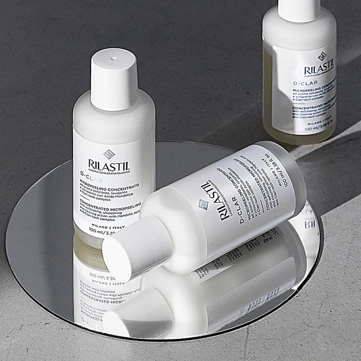 Rilastil skincare bottles on a reflective surface with a dark background