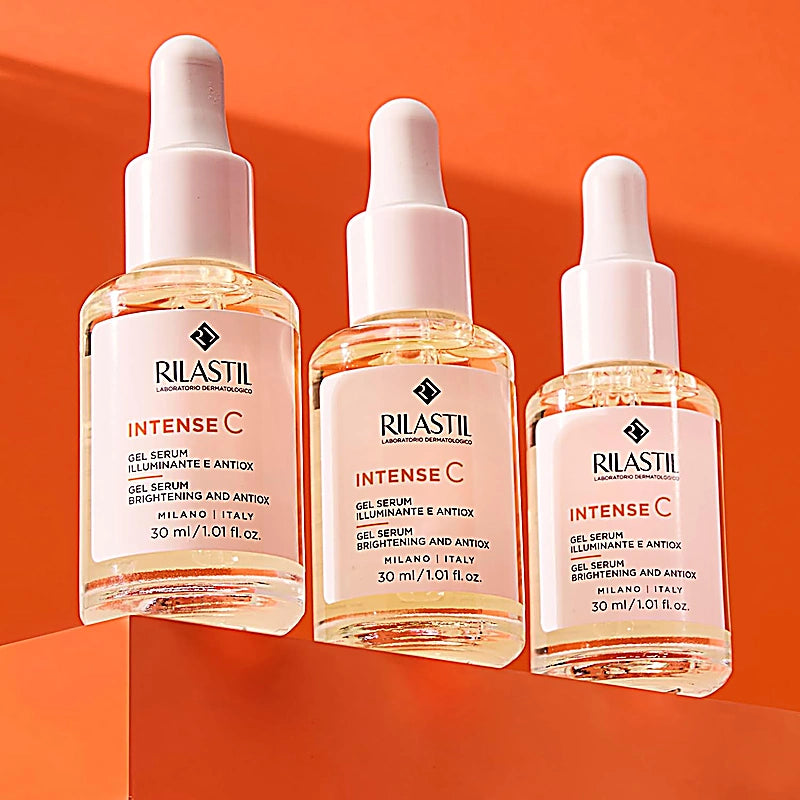 Three bottles of Rilastil Intense C skincare serum on an orange background