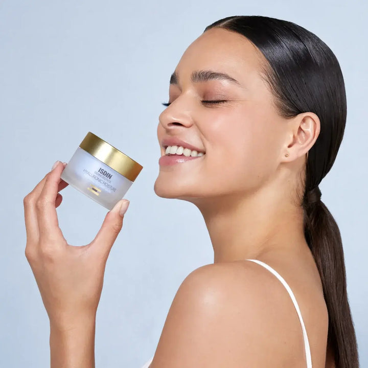 Woman holding ISDINCEUTICS Hyaluronic Moisture Cream for normal to dry skin with radiant complexion