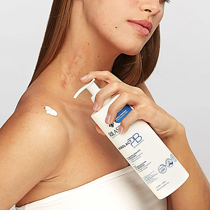 Woman applying a skincare product to her shoulder with a white background