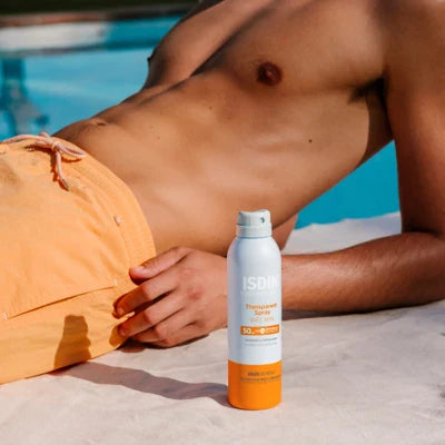 ISDIN Fotoprotector Transparent Spray SPF50 body sunscreen bottle near person in orange swimwear by pool