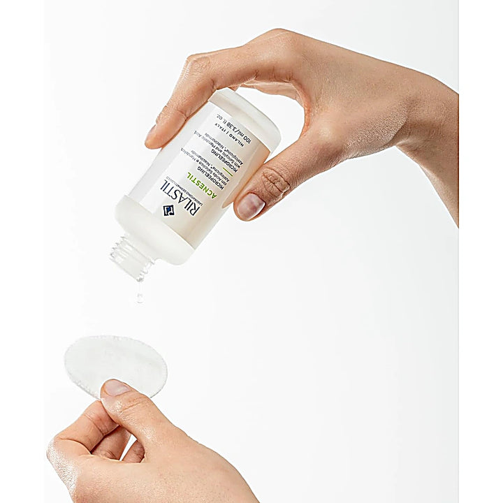 rilastil-acnestil-micropeeling-100ml-serum pouring down on cotton pad